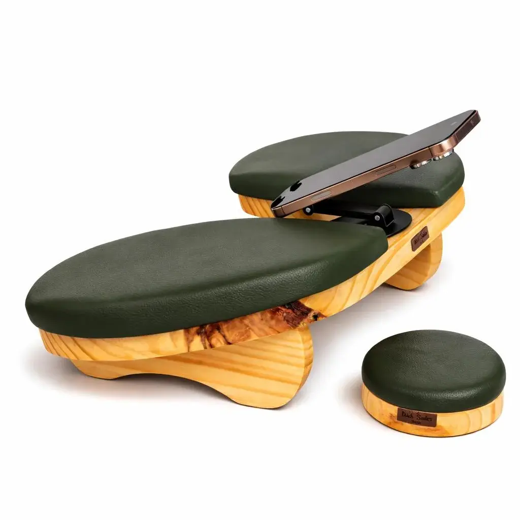 Kit Delta Pro Rustic com estofado verde-musgo: apoio de braço em madeira rústica com suporte de celular segurando um aparelho, ao lado do apoio de cotovelo redondo